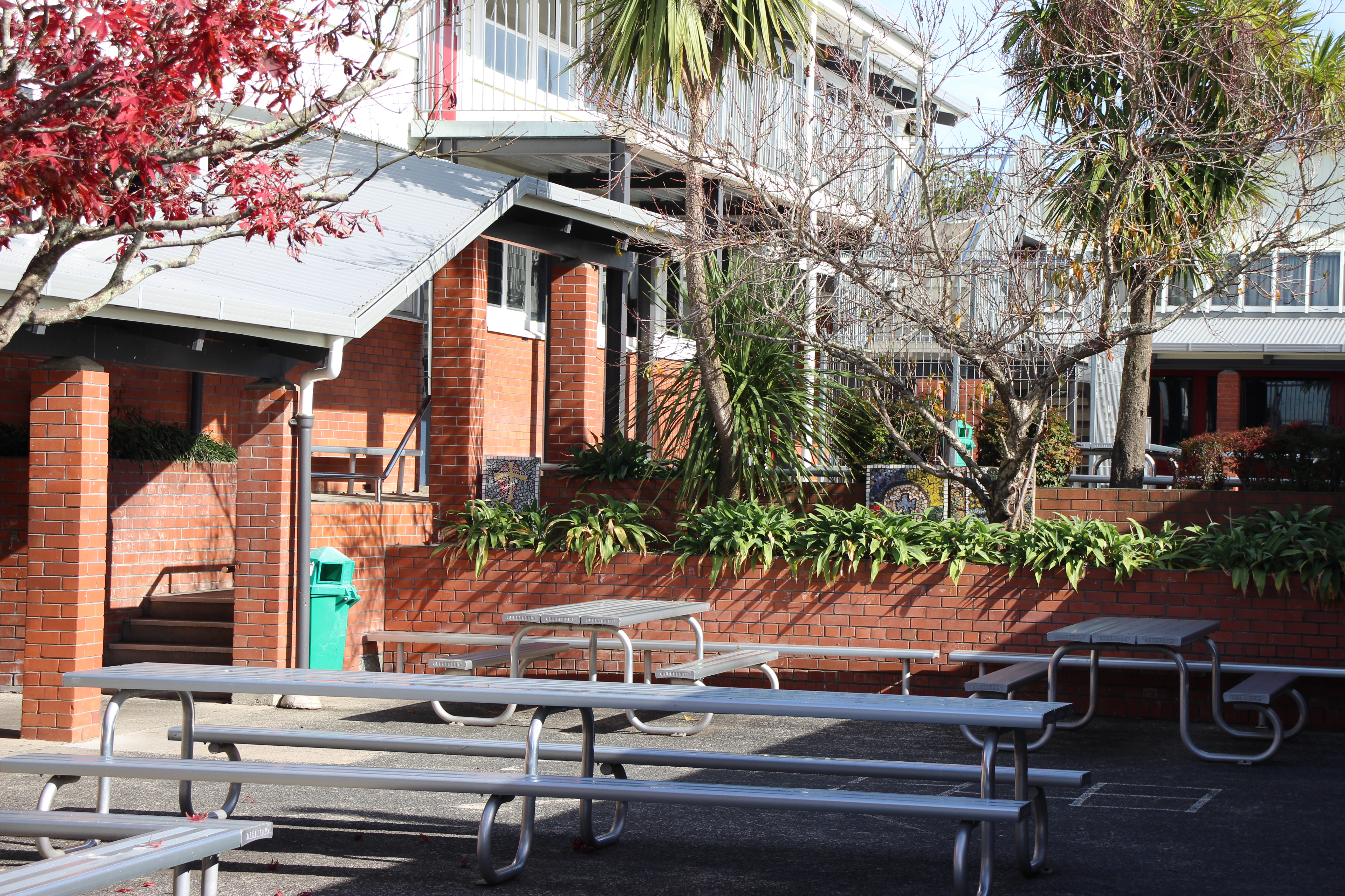 Brick school buildings exterior with trees and tables