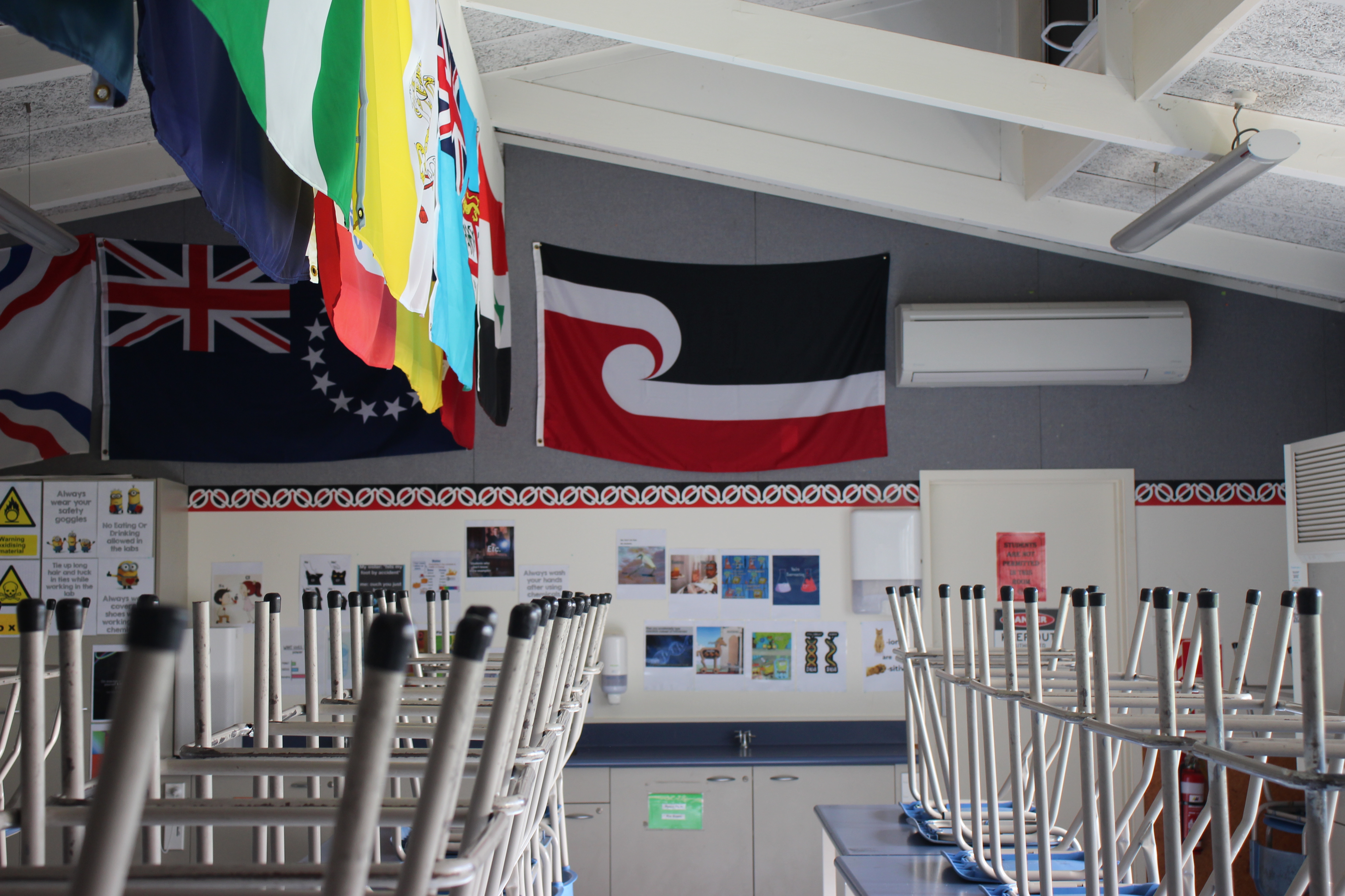 Classroom with chairs up for the holidays and flags displayed on wall 