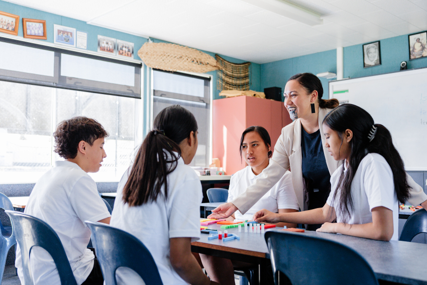 Teacher happily speaking with secondary students in the classroom