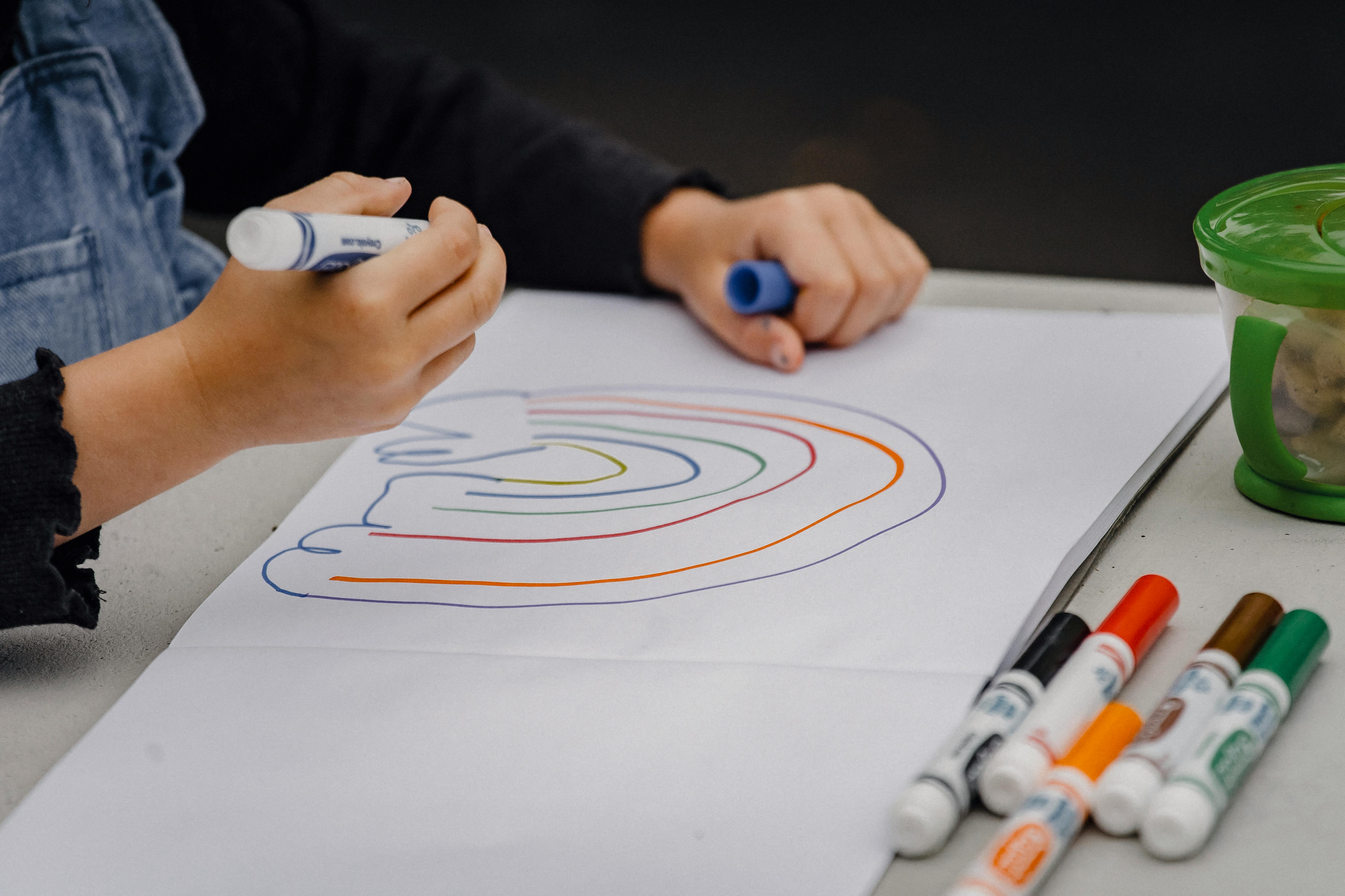 Childs hands as they draw a rainbow on paper 