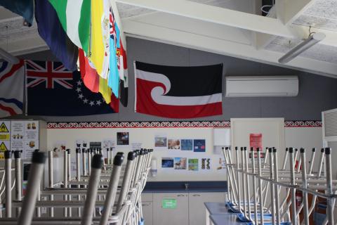 Classroom with chairs up for the holidays and flags displayed on wall 