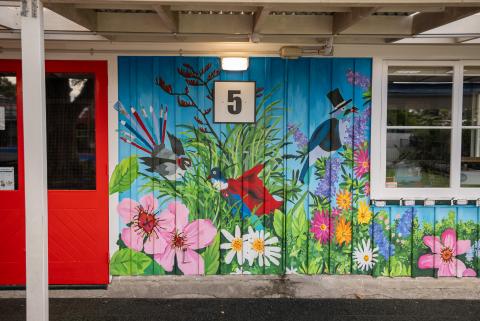 a colourful nature mural with birds outside a school classroom 