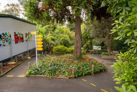 Exterior of schools with tress, mural on a classroom and signage on a pathway