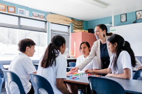 Teacher happily speaking with secondary students in the classroom