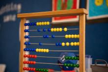 A close up photo of an abacus with a classroom wall and posters in the background